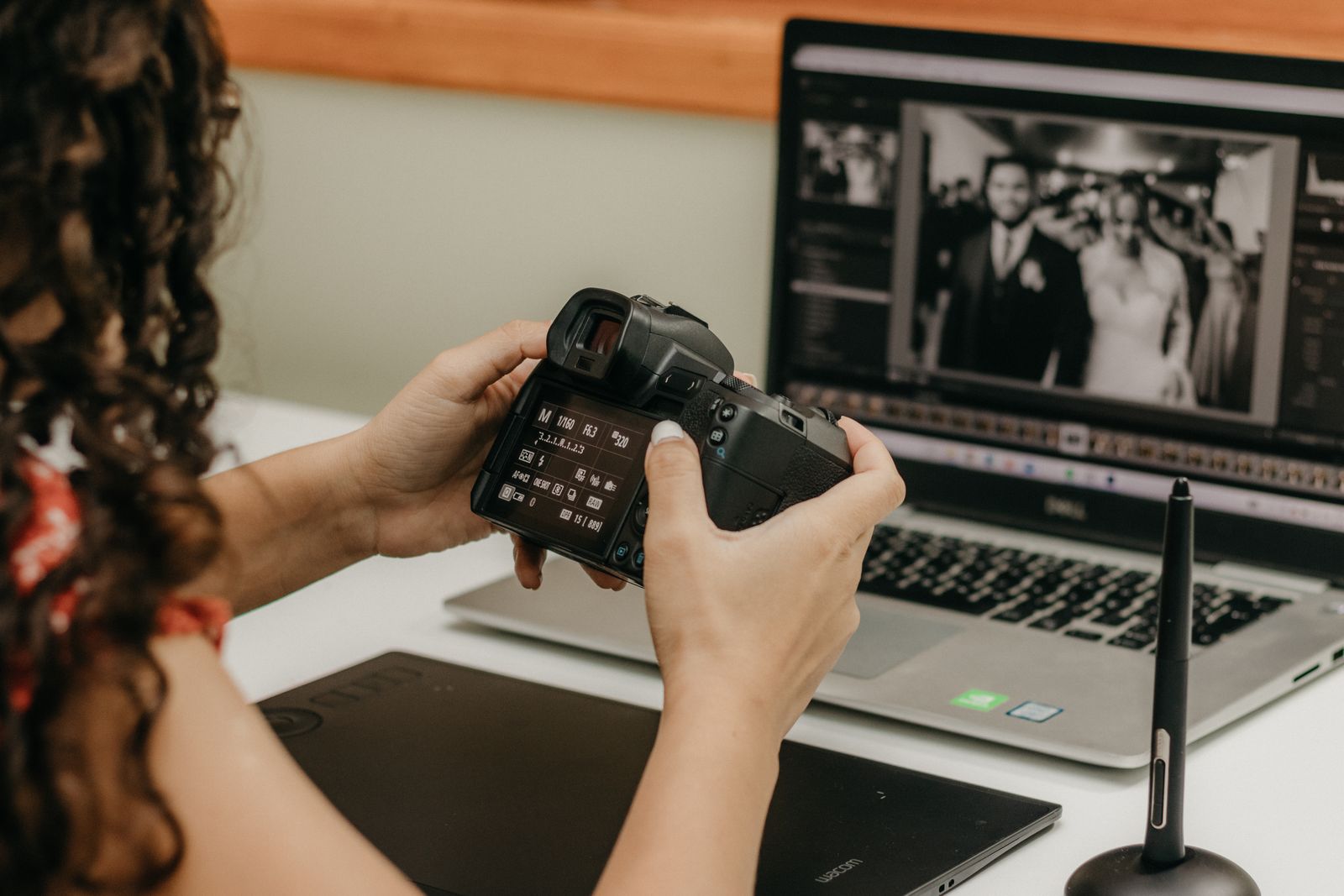 A photographer editing wedding photos on a laptop, camera in hand