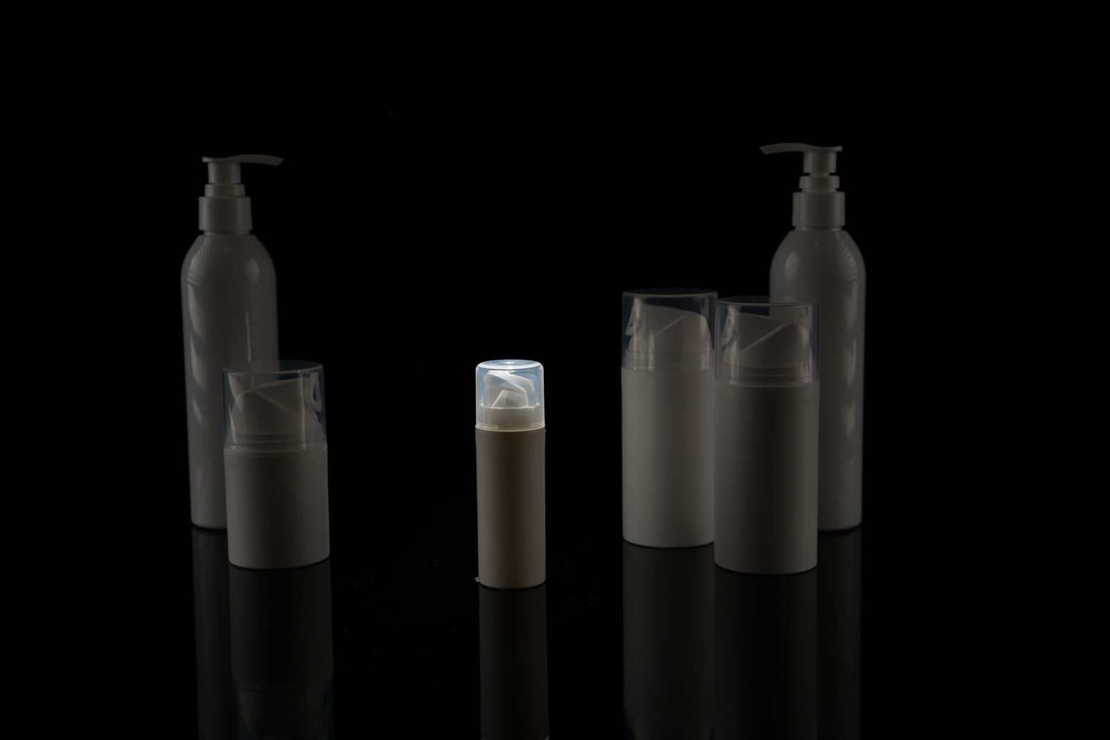 Cosmetic bottles arranged against a dark background for a commercial shoot