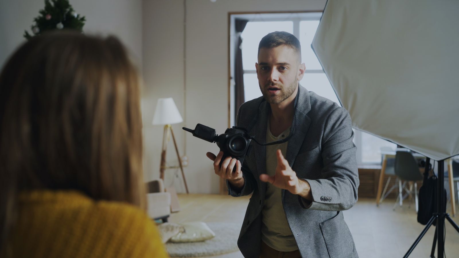 A photographer directing a portrait subject beside a large studio window