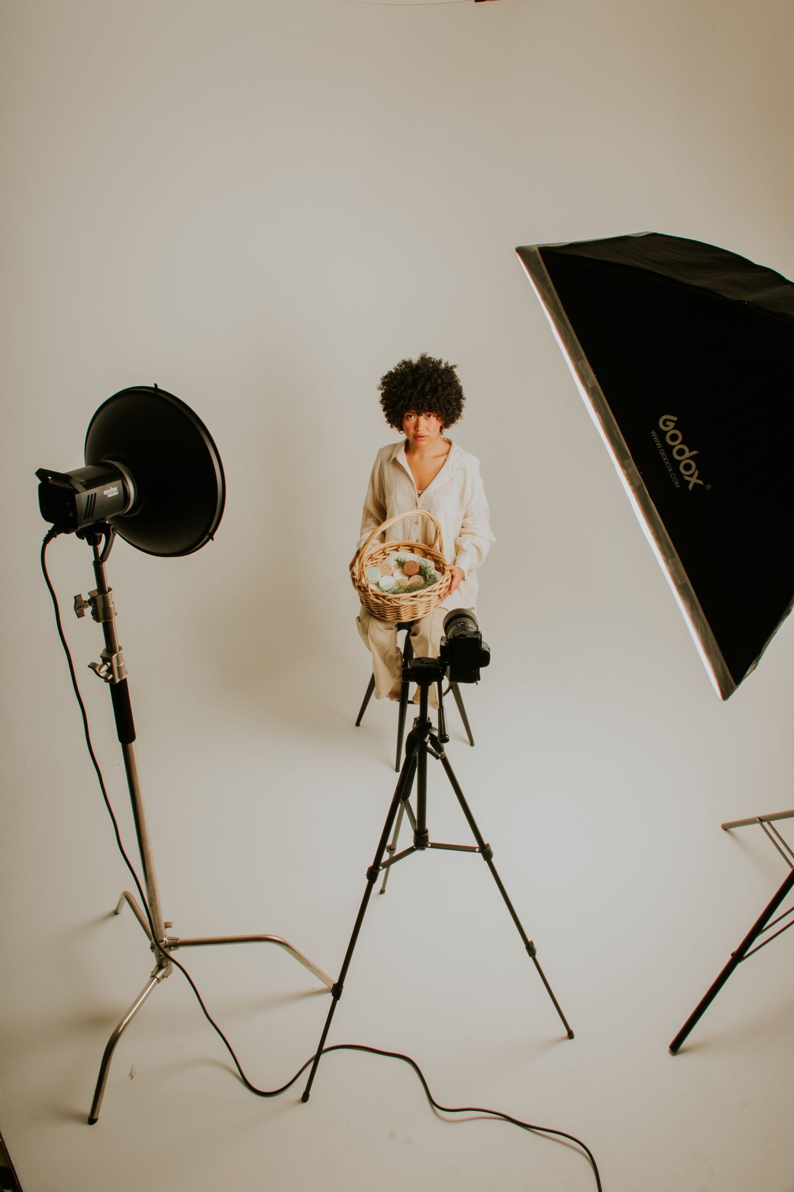 A model posing with a prop basket surrounded by studio lighting