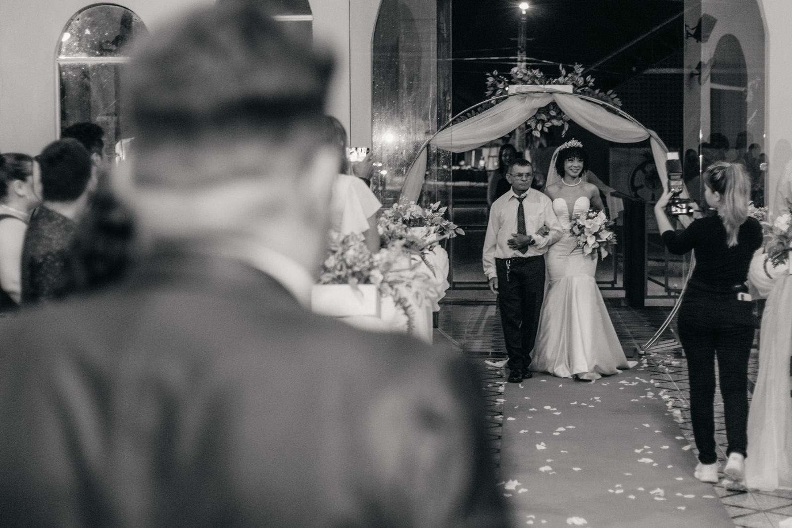 A bride walking down the aisle with her father at an indoor wedding ceremony